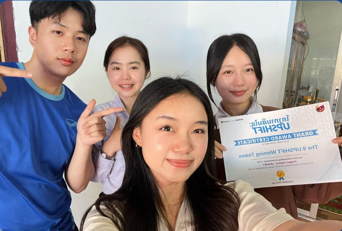 Team Social Spark, the Breath of Fresh Air project from Luang Prabang — four participants in a close group photo indoors, one holding their grant certificate.