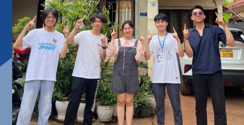 Team Shark4, the SalaSara project from Vientiane — five participants posing outdoors in front of a house and car, each pointing upward.